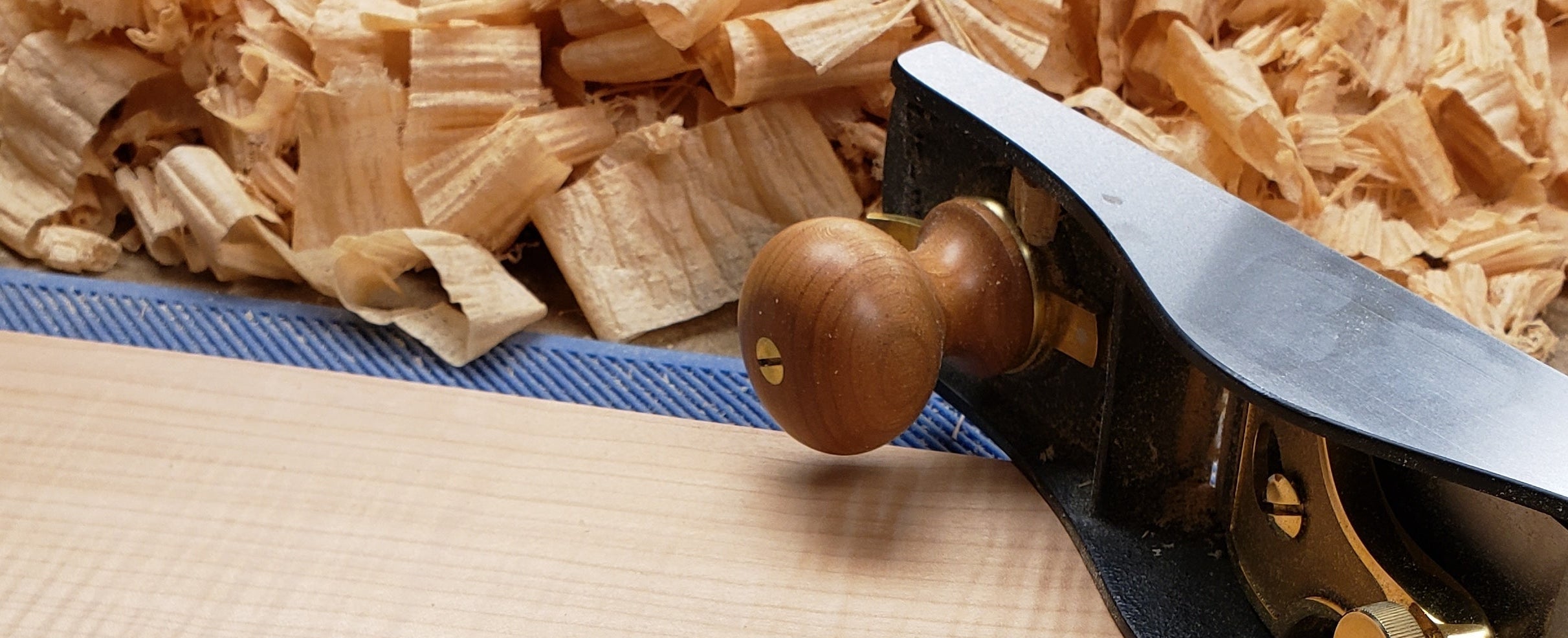Wooden plane tool on a wooden surface with wood shavings in the background